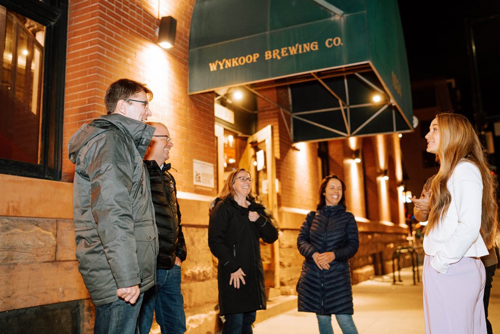 Five alumni talk outside in a circle outside of the Wynkoop Brewing Co.
