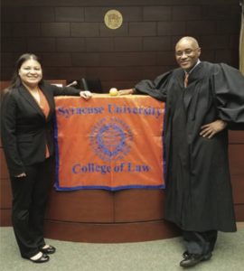Anna Castillo L’16 and Hon. Rodney Thompson L’93, G’93 in courtroom with SU COllege of Law flag