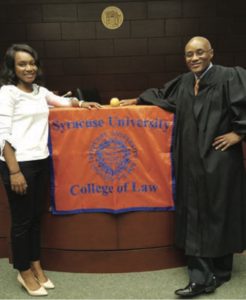 Ursula Simmons L’19 and Hon. Rodney Thompson L’93, G’93 in courtroom with SU COllege of Law flag