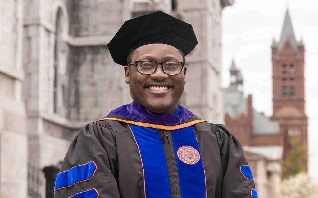 Linton in his cap and gown on the Syracuse University campus