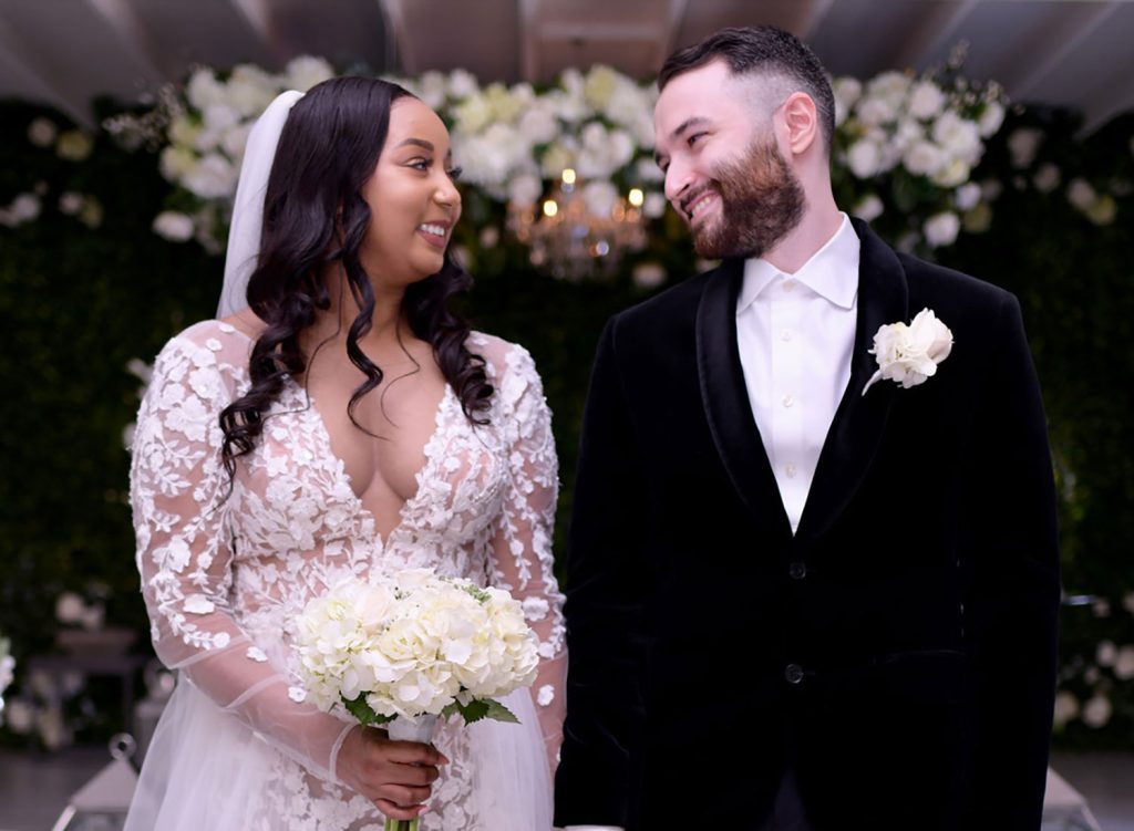 Adam and Marlana smile at each other in a wedding photo, her in a white dress and him in a tux