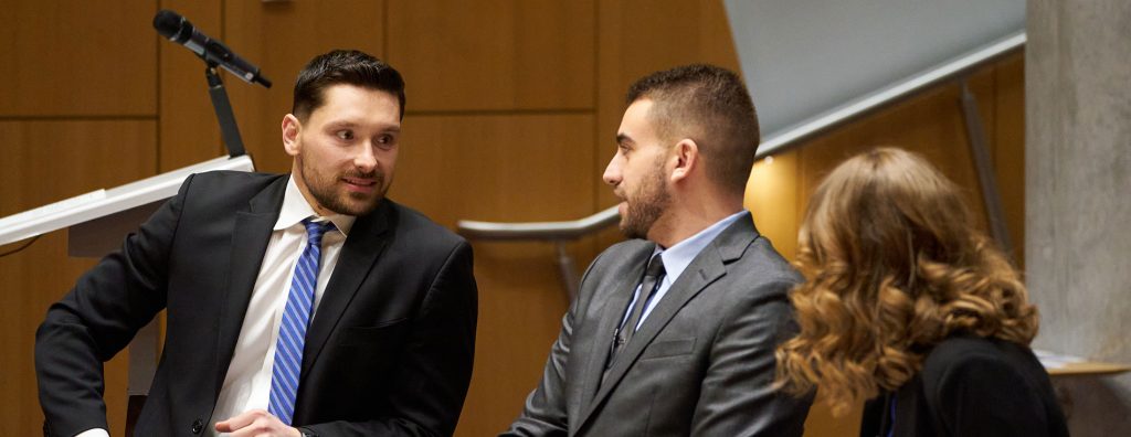 three students talk in the courtroom during an advocacy competition