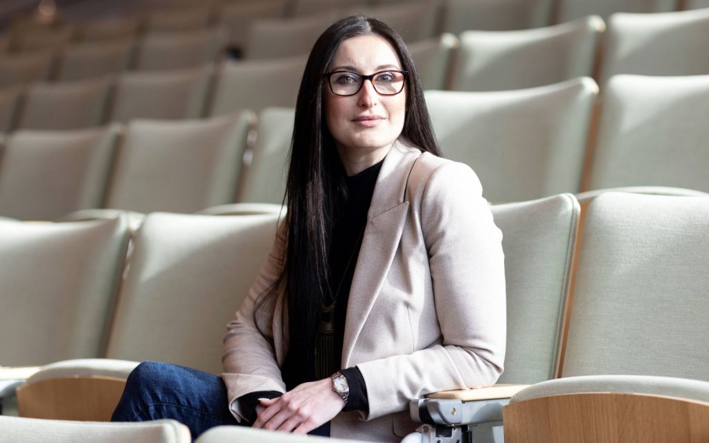 Allison Carlos sitting in courtroom seats looking at camera
