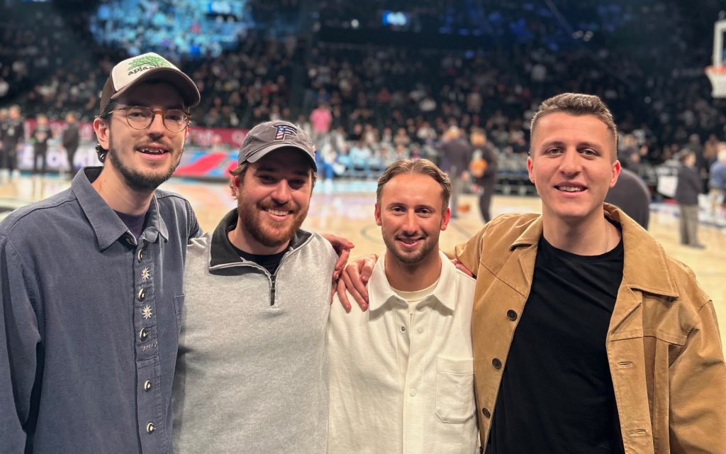 Zachary Mazuzan at a Brooklyn Nets game smiling for the camera courtside with three other friends
