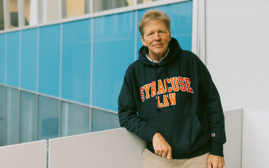 George poses for the camera in a Syracuse Law sweatshirt