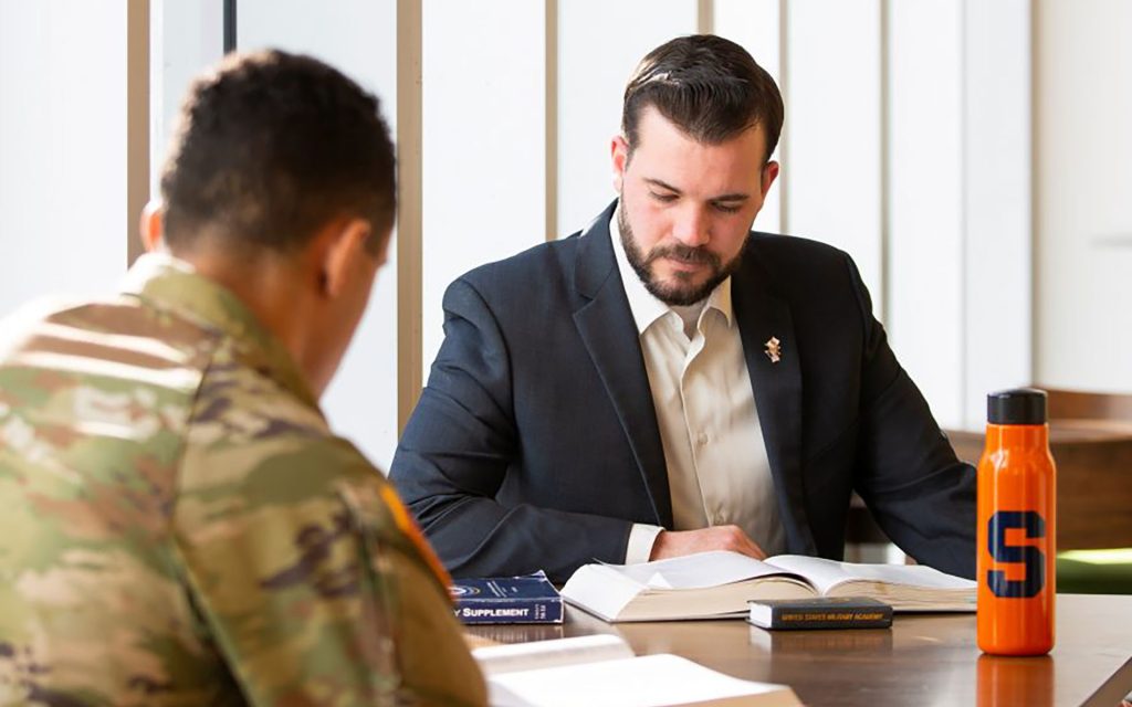 Veteran sitting with a student in the library going over paperwork at a table