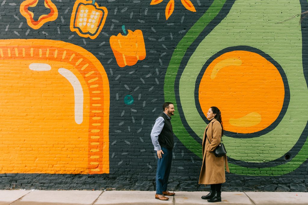 two students standing in front of a mural at salt city market