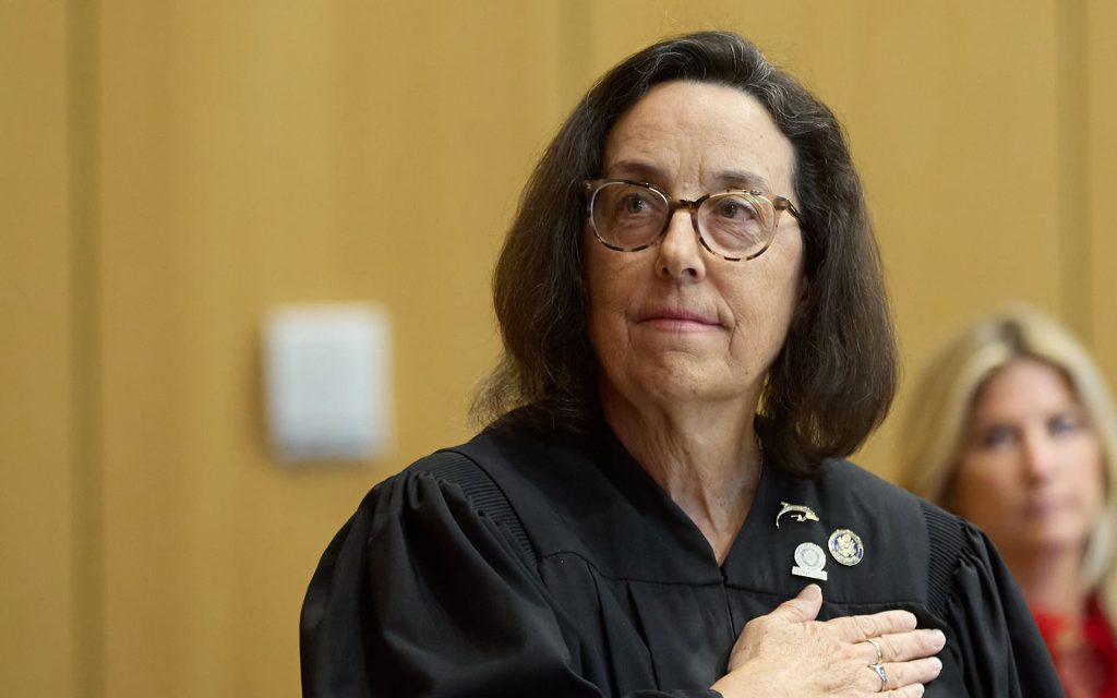 Hon. Thérèse Wiley Dancks L’91 looking away with hand over her heart in Judges robe.