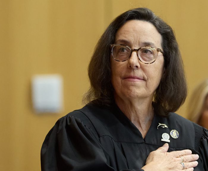 Hon. Thérèse Wiley Dancks L’91 looking away with hand over her heart in Judges robe.