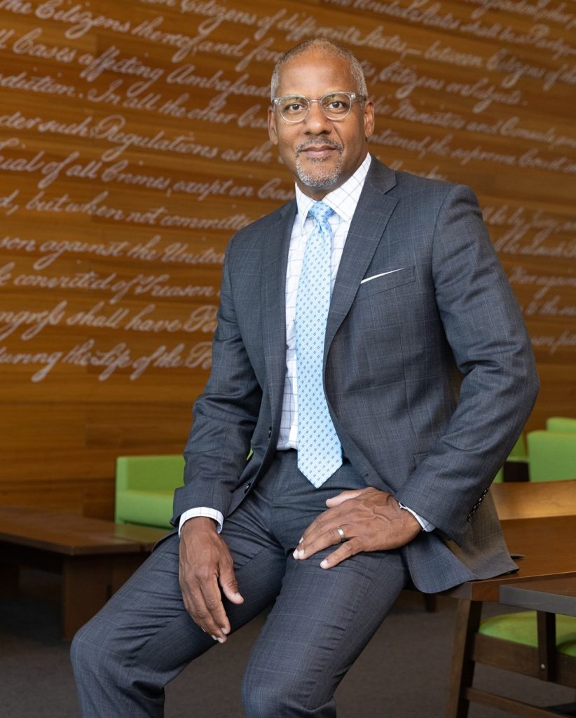 A man in a suite sitting on a table