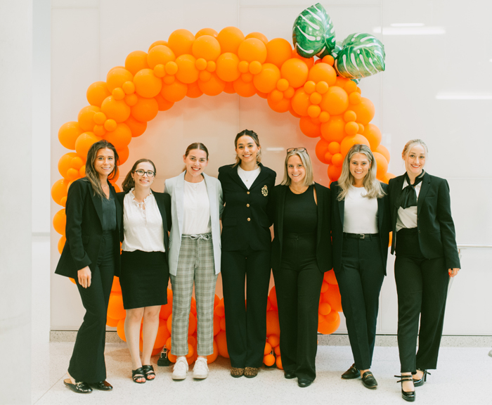 A group of students standing in front of an orange made of balloons