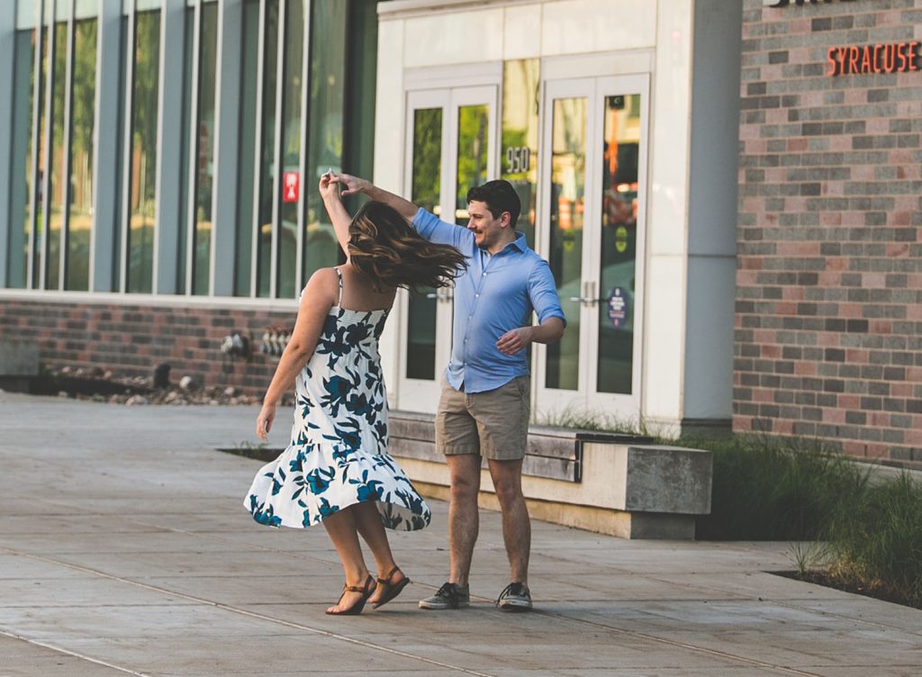 Marshall twirls Gabriella in a dance move in front of the law school building outside
