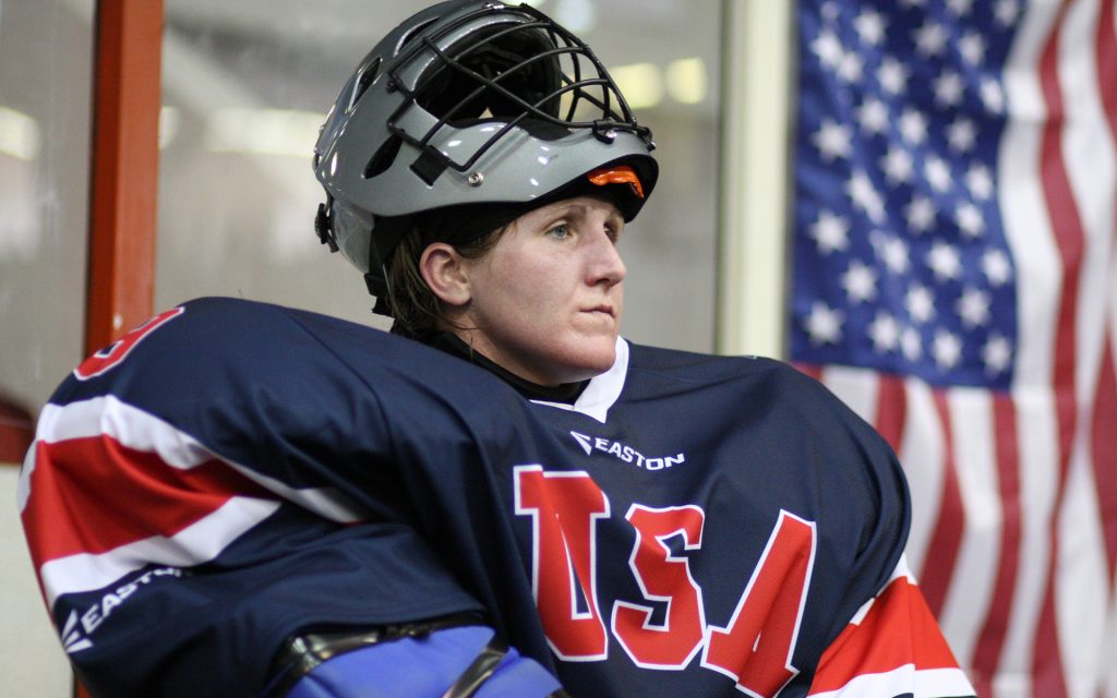 Ginny Capicchioni in her lacrosse uniform for team USA, with a flag in the background