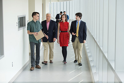 Jack rudnick walking down a bright hallway with students