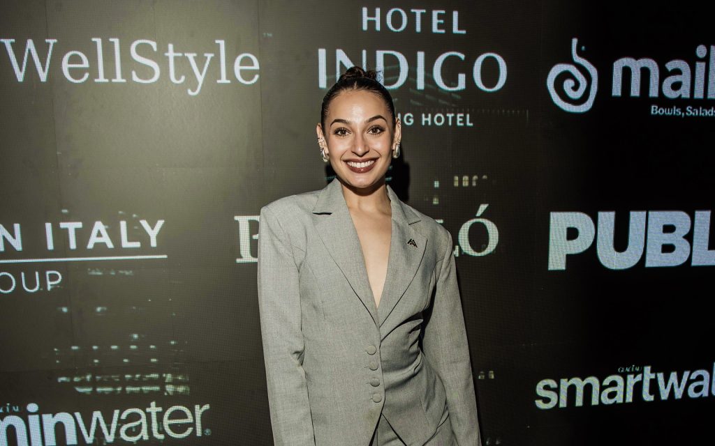 Headshot of Jill Nelsen at Miami Swim Week in front of a step and repeat wearing a gray suit