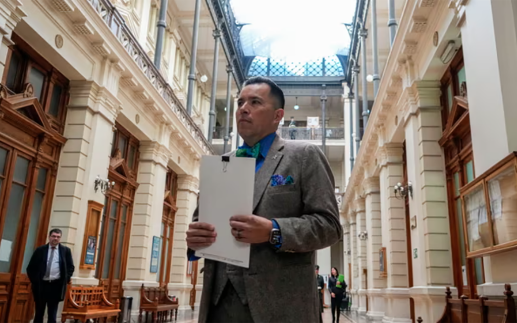 Jimmy Gonzalez stands in the Supreme Court in Chile to file his lawsuit with a stack of papers.