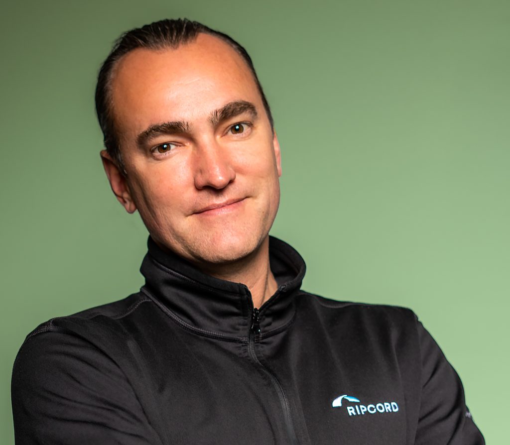 Headshot of Kevin Whittaker wearing a black Ripcord pullover in front of a green background 