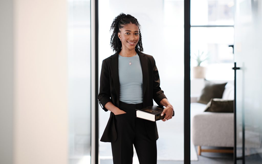 Lela Lanier stands while holding a book and wearing a black suit at her NAACP internship