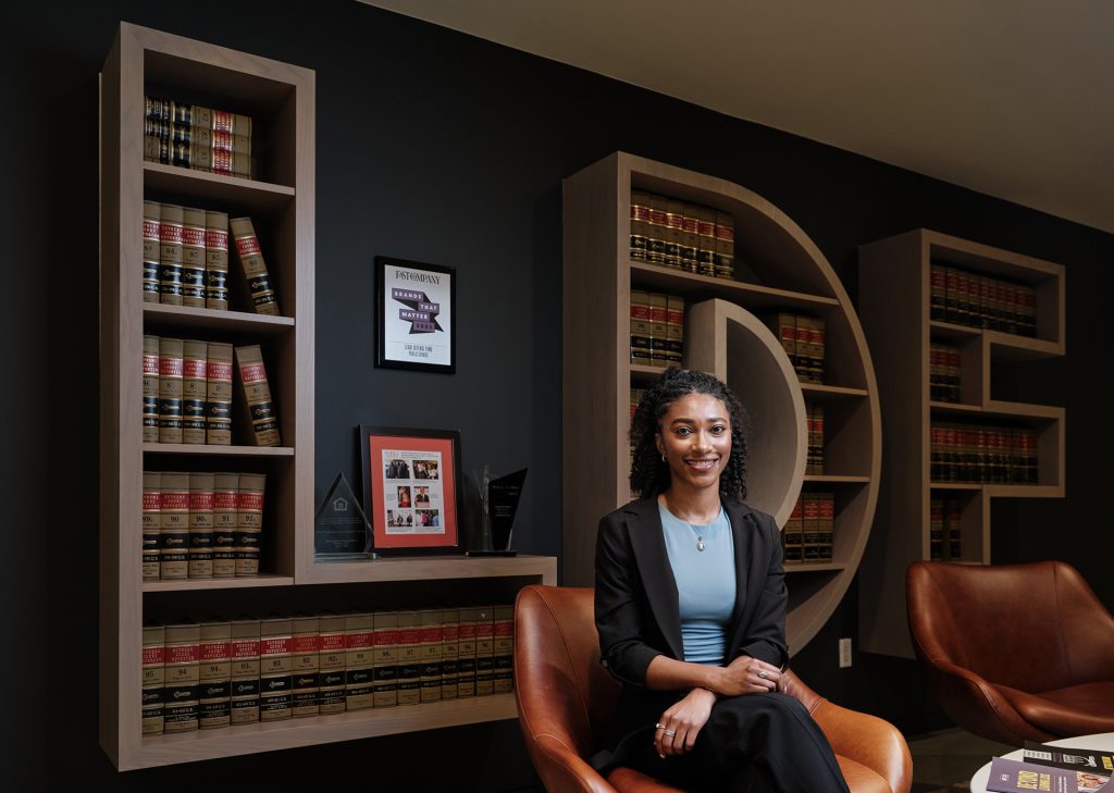 Lela Lanier sits in front of an LDF sign that is full of books  in the lobby of the NAACP