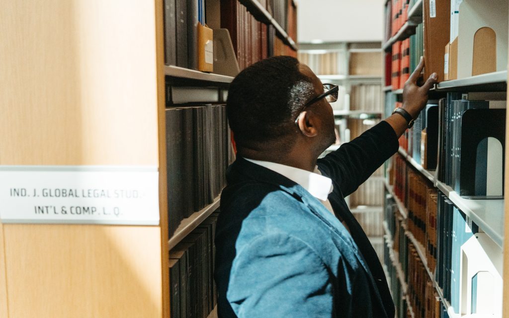 Linton reaches for a book on a library shelf