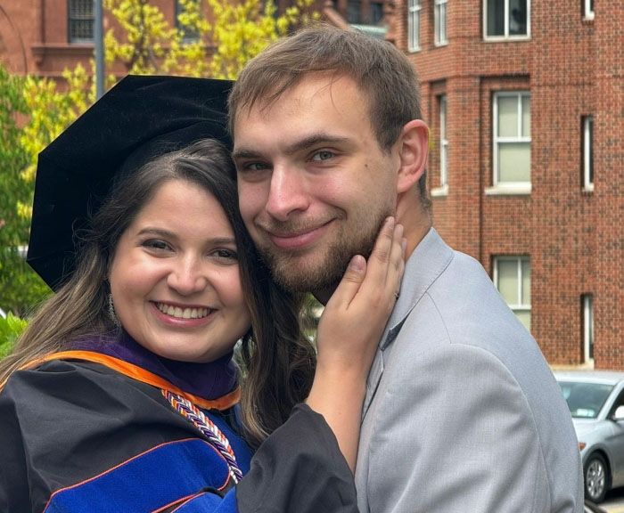 Luiza and Aric smile together, her in a cap and gown and him in a gray button down shirt