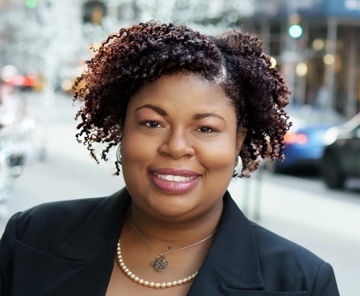Headshot of Mary Goodwin Oquendo with city streets in background.