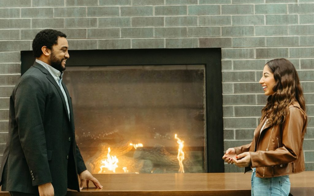 Maheen and James Cameron laughing in front of the fireplace in Dineen Hall