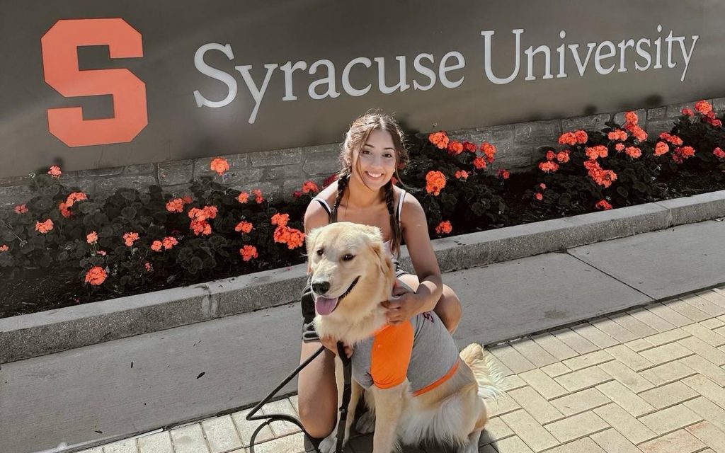 Maheen and her dog Clifford in front of the Syracuse University sign