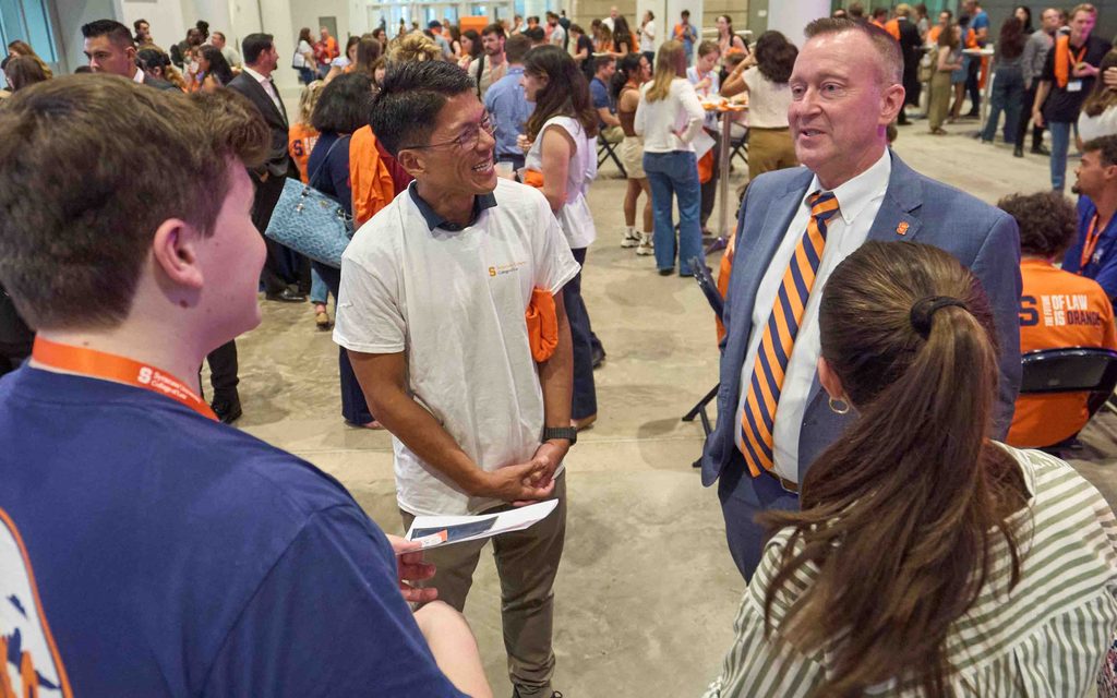 Syracuse University Chancellor Michael Haynie and Dean Terence Lau L'98 speak with members of the incoming class. 