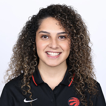 headshot of Niloo smiling at the camera in front of a white background, wearing a basketball polo 