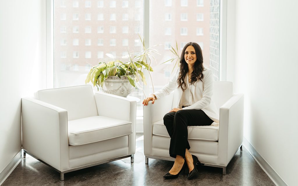 Omnia sitting in a white chair in front of a window background