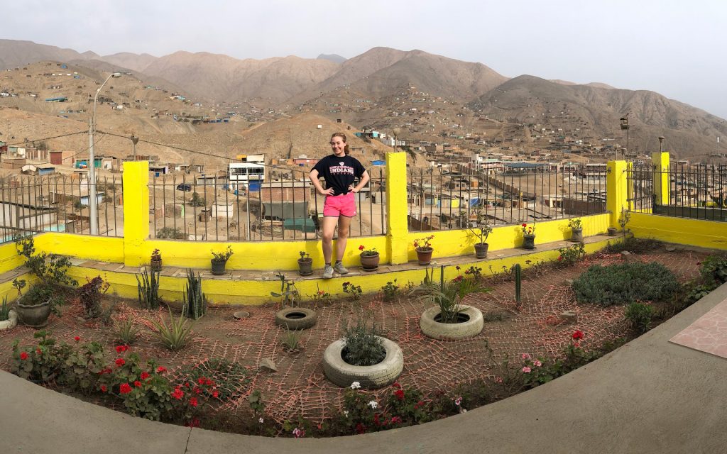 Meghan Wright standing on a yellow ledge in front of a mountain range in Peru