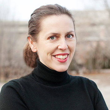 headshot of Sarah Roberts smiling in a black turtleneck in front of an abstract outdoor background