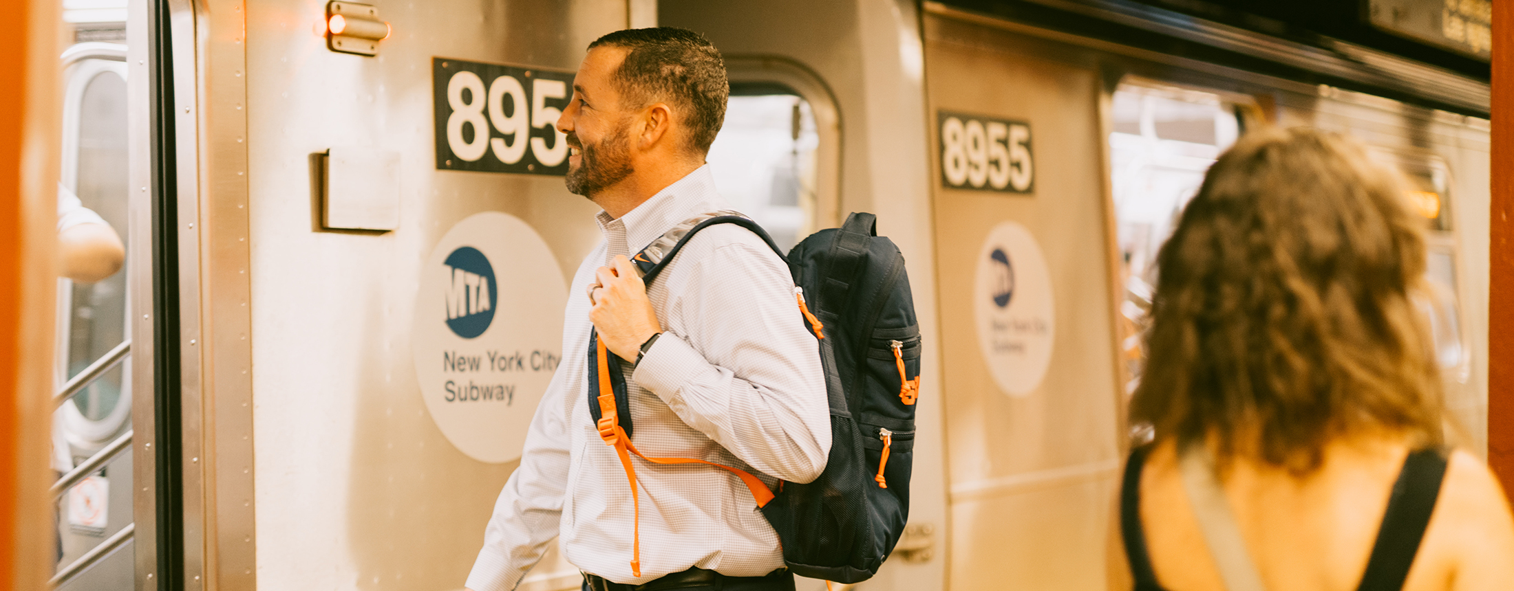 student with a syracuse backpack about to get on the new york city subway