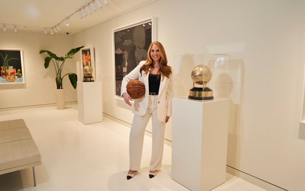 Dana stands next to a trophy holding a basketball