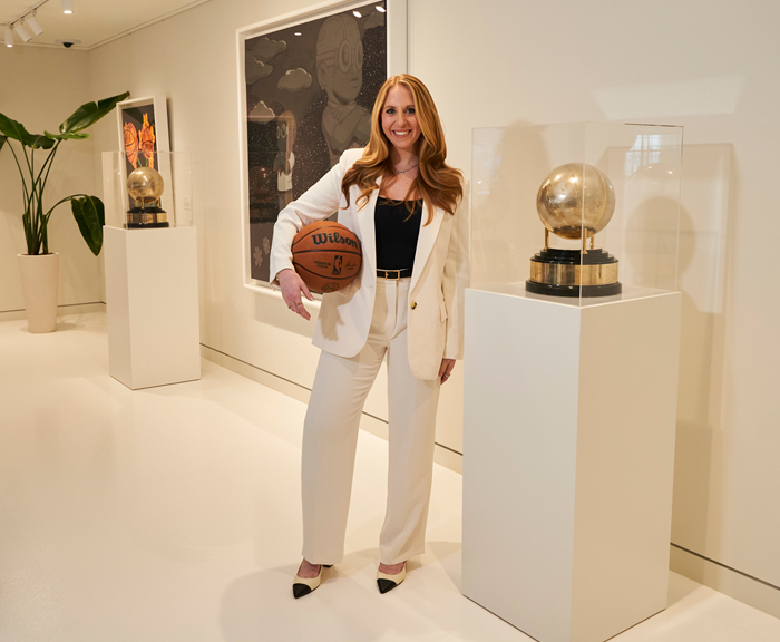 Dana stands next to a trophy holding a basketball