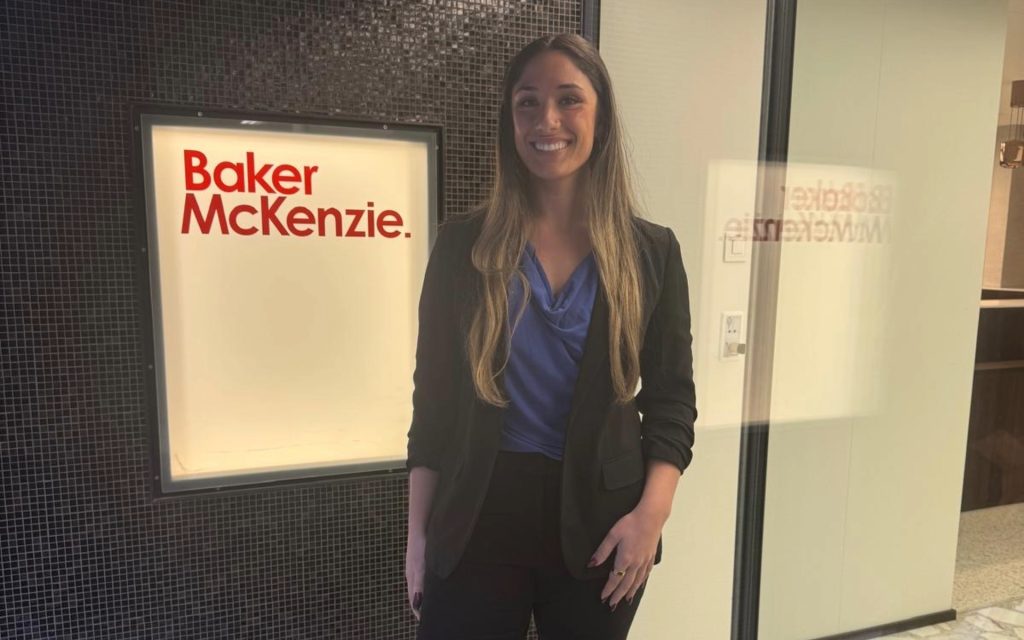 Syracuse University Law Student standing in front of Baker McKenzie sign in Switzerland.