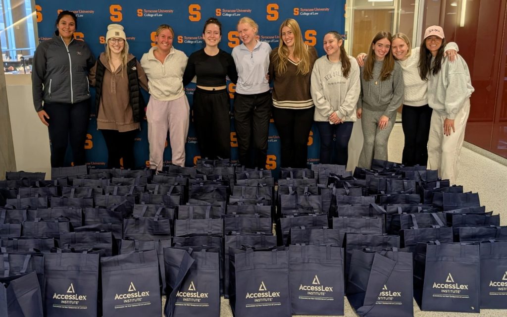 SU College of Law students standing in front of a banner and blue accessLex gift bags